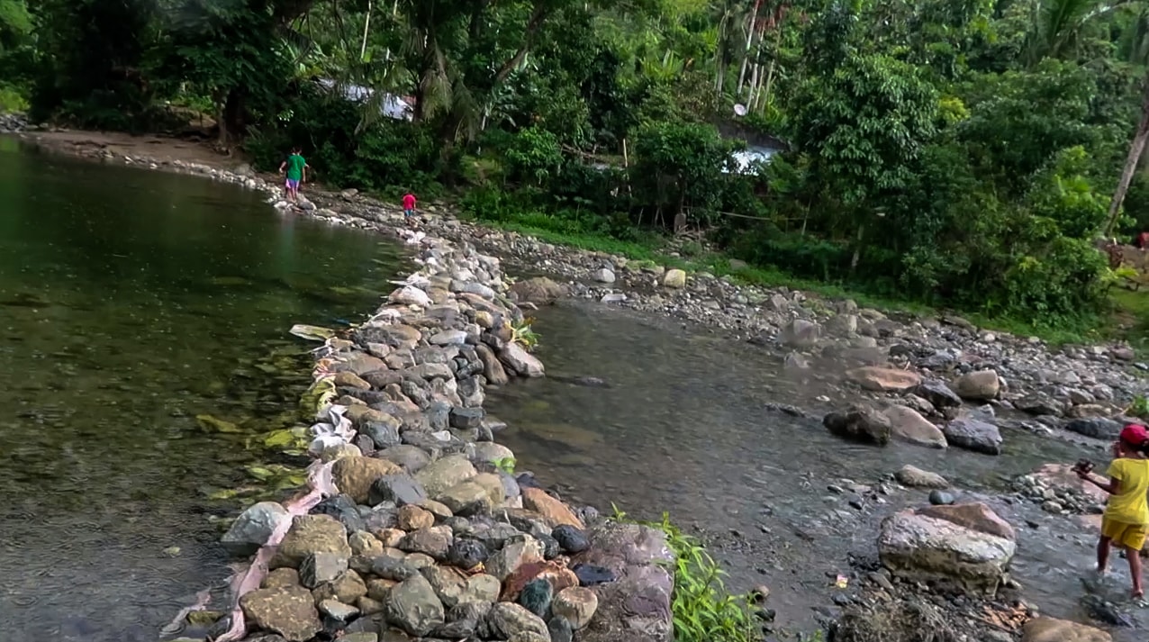filipino kids walking over rock in river in catanduanes philippines